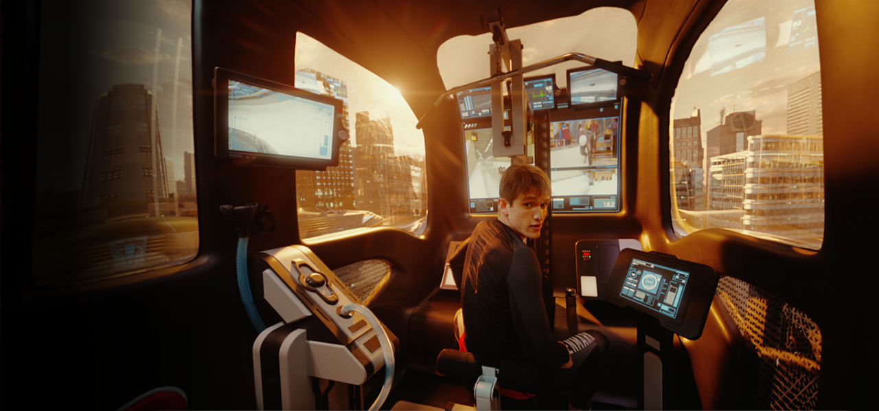 Rear view of a young man, sitting in the driver's seat of a Toyota e-Palette, which has a very modern and tech-y looking interior. The man is turned around to look at camera.